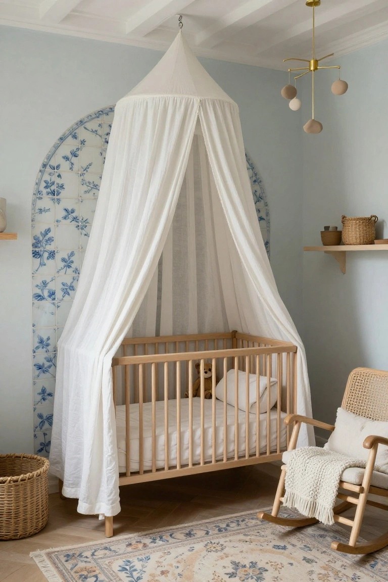 Wooden crib with white sheer canopy under an arched wall of blue floral tiles in a pale blue nursery room with rocking chair and woven baskets.