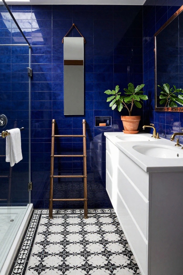 Bathroom with deep blue subway tiles covering three walls, glass shower enclosure, copper ladder towel rack holding white towels, double white vanity with brass faucets, potted fiddle leaf fig plants, and black-and-white patterned floor tiles.