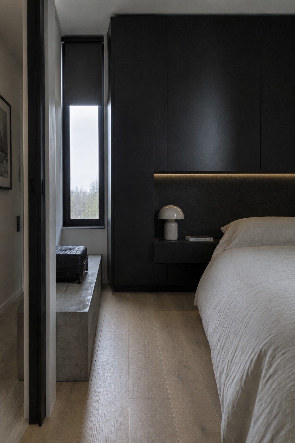 Modern bedroom with black cabinetry, white bed linens, mushroom lamp, and wood floors.