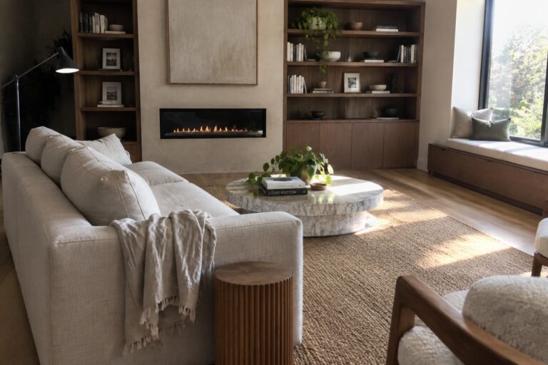 19 Modern Home Interior Ideas Featuring Built-In Storage A living room with built-in wooden bookshelves flanking a linear fireplace, a light-colored sofa, a marble coffee table, and a large jute rug on hardwood flooring.