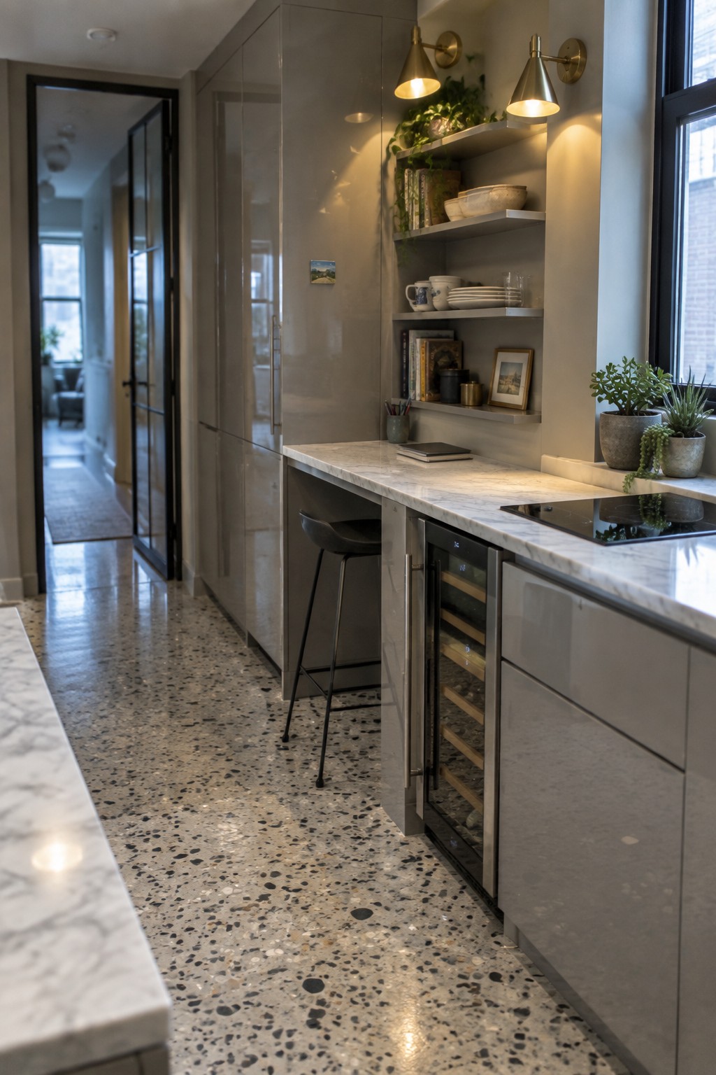 A modern kitchen with full-height gray cabinets, marble countertops, a built-in wine refrigerator, open shelves, a black bar stool, and a terrazzo floor.