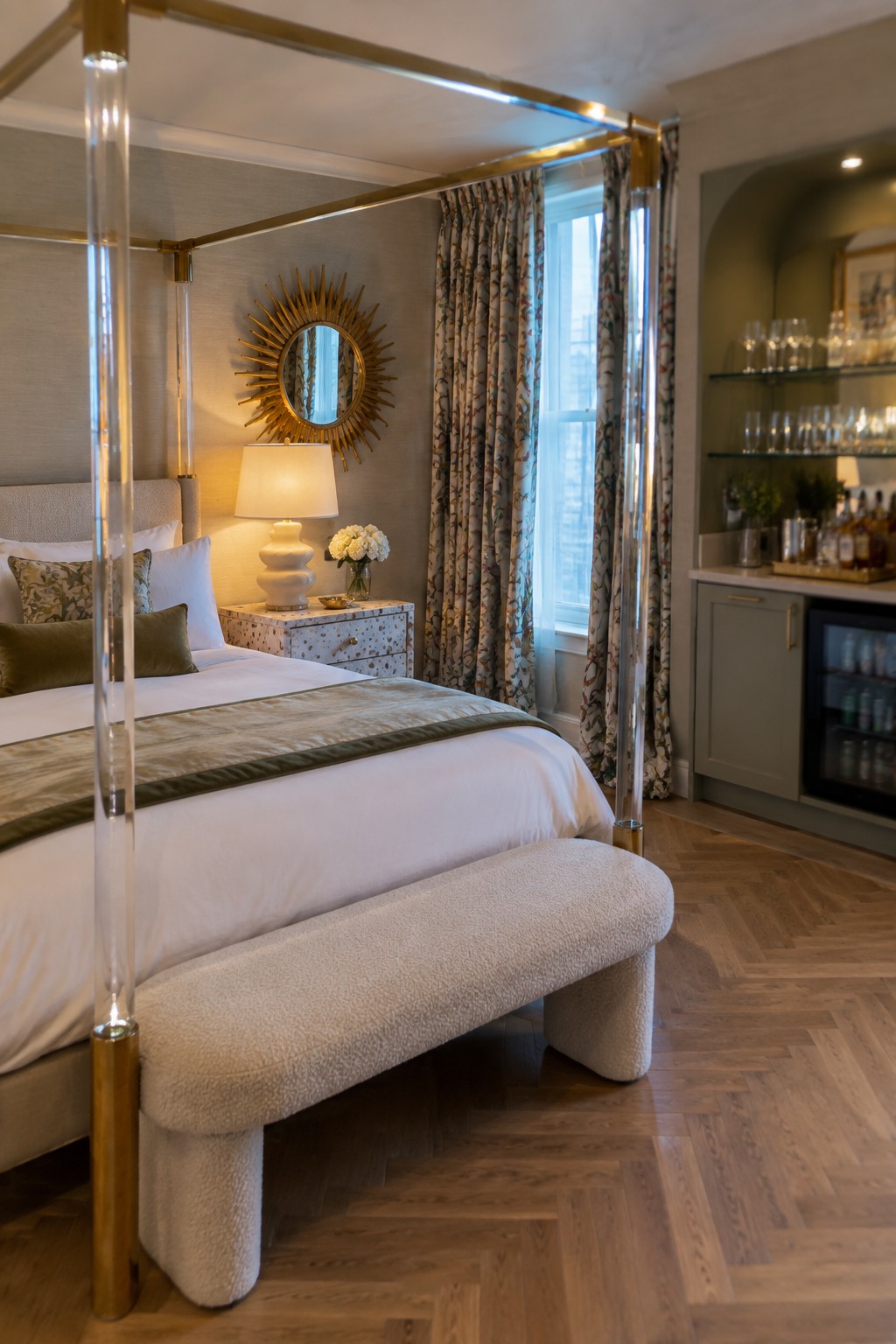 Luxurious bedroom with clear acrylic four-poster bed, white linens, sunburst mirror, and bar