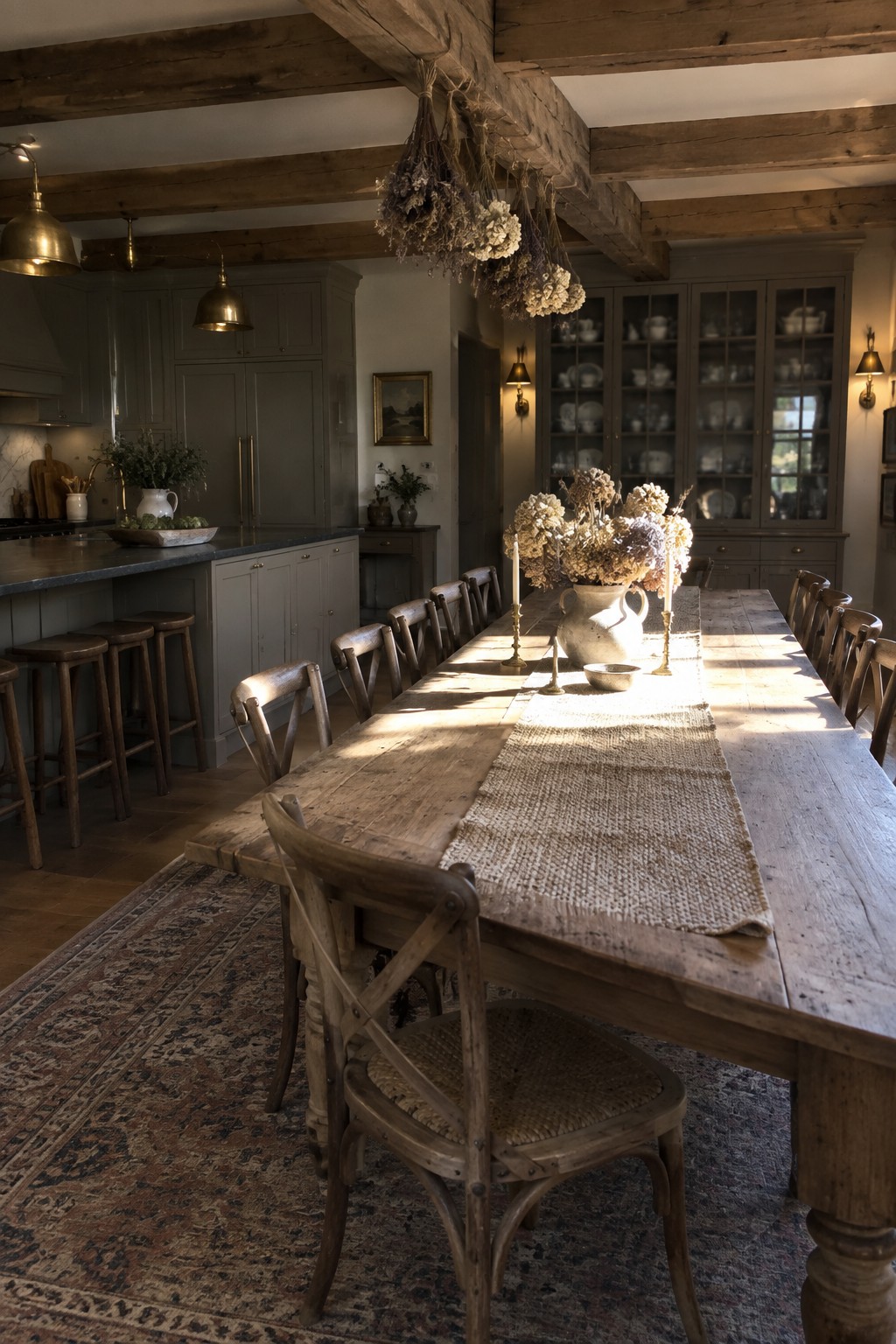 Rustic wooden dining table with dried flowers, chairs, and gray cabinets in sunlight