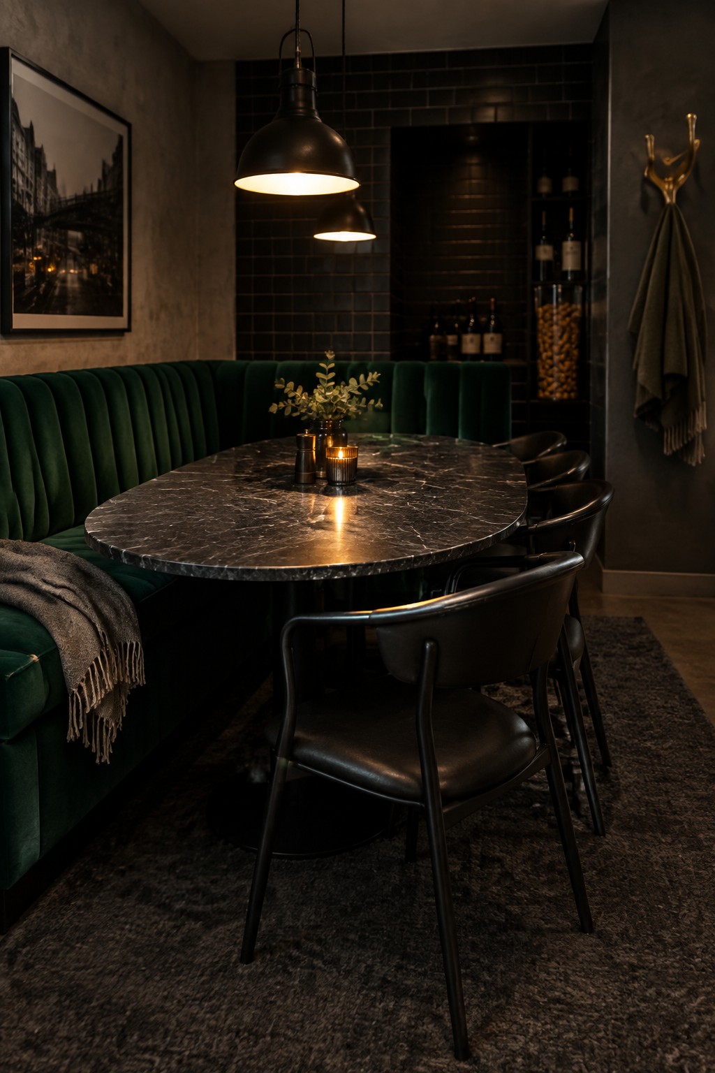 Elegant dark dining space with green velvet booth, marble table, black chairs, and pendant lights.